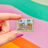 Hand holding andys room stamp enamel pin