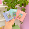 Hand holding Stamp Enamel Pins of White City, Lorien, Asgard