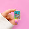 Hand Holding the Atlantica Stamp Enamel Pin.