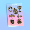 Dark Magic Enamel Pin Collection of 7 pins featuring The Ring, Tom Marvolo Diary, The Locket, The Diadem, The Snake Nagini, Wizard glasses, and Helga's Cup