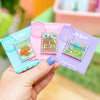 Hand holding stamp enamel pin of Laputa, The Bakery, The Valley of the Wind