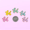 Balloon Dog Enamel Pins in Yellow, Teal, Blue, Pink and Purple on colorful paper.