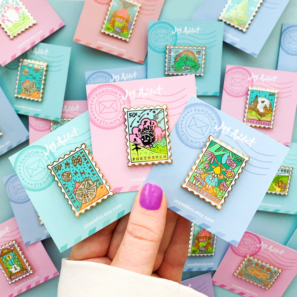Colorful Display in frame of Mix and Match Stamp Enamel Pin Set, Porthaven, Neverland, A Galaxy Far Far Away, Tulgey Woods, The Magical Castle for Wizards, Pemberley, Wizard of Oz, The Safari Dinosaur Island, The Wardrobe, Bag End, Dune, Anne of Green Gables